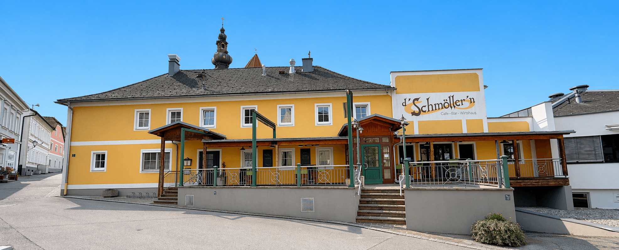 Außenansicht des D'Schmöllern, historisches gelbes Gebäude mit Café-Bar-Wirtshaus-Schild in Gunskirchen